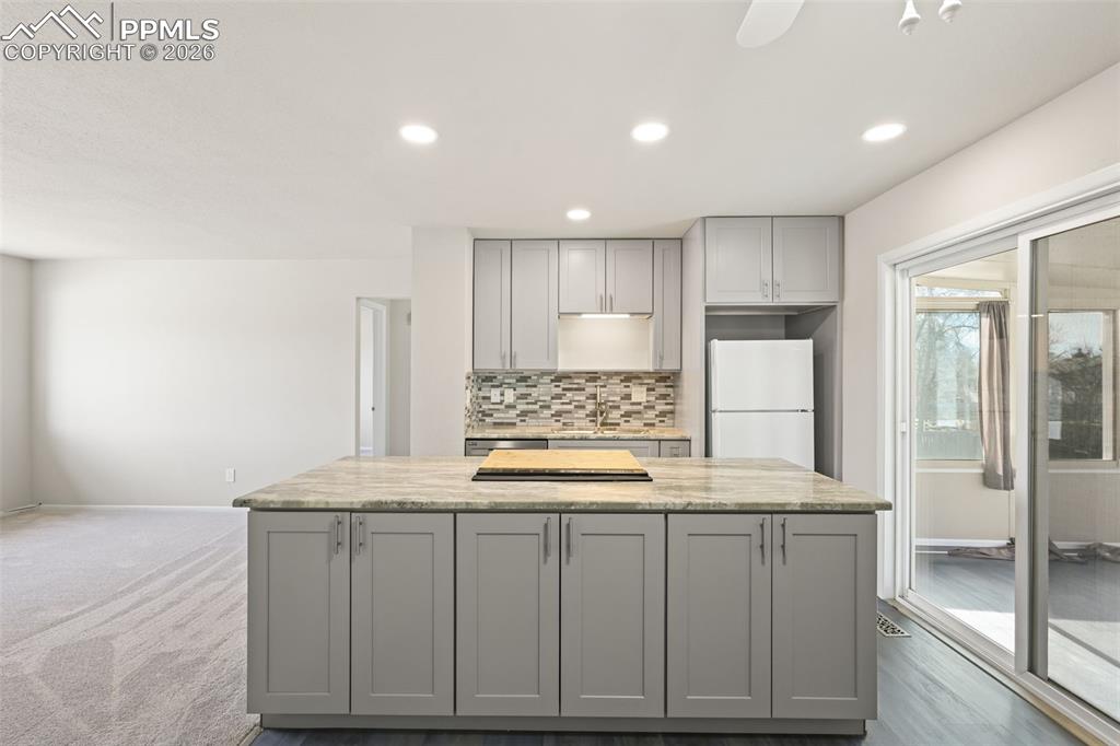 1620 Winnebago Road Colorado Springs, CO 80915 - Photo 7 of 25 a kitchen with kitchen island granite countertop white cabinets and refrigerator