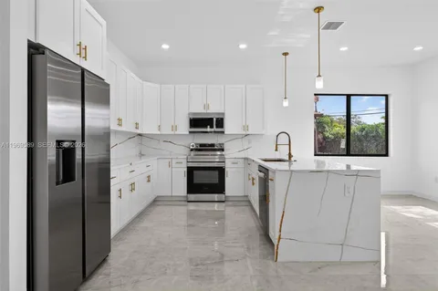 a kitchen with a refrigerator oven a sink a window and white cabinets