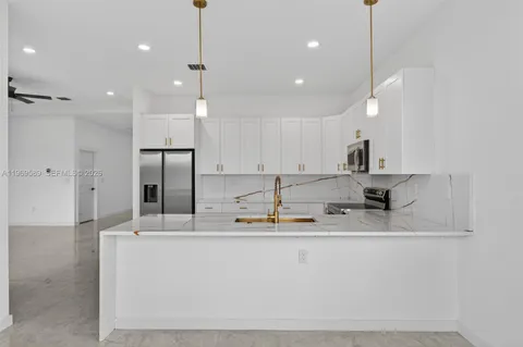 a kitchen with kitchen island stainless steel appliances sink refrigerator and microwave
