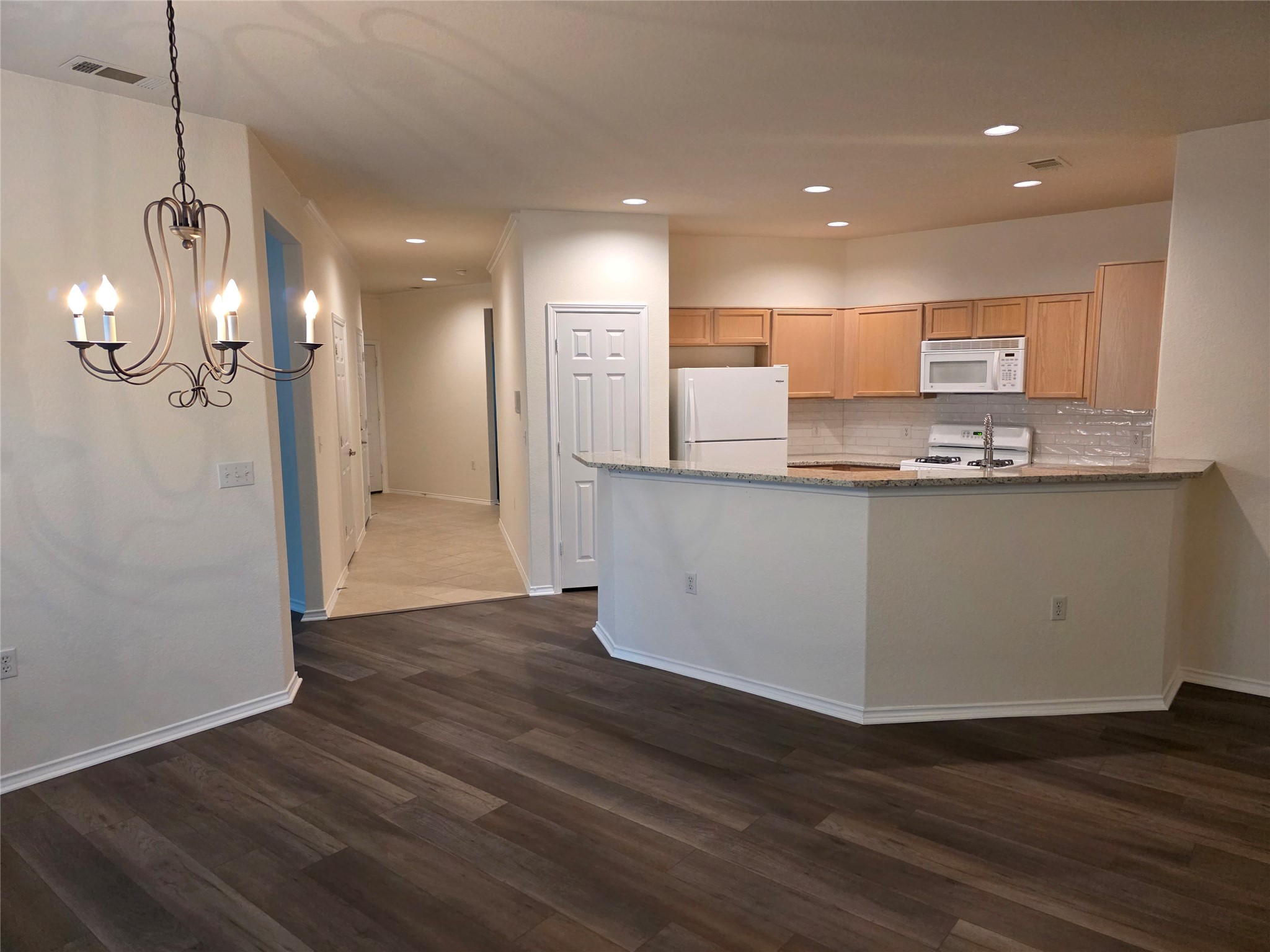 201 Yosemite Road Georgetown, TX 78633 - Photo 8 of 21 Kitchen with light brown cabinets, light stone countertops, a peninsula, white appliances, and recessed lighting