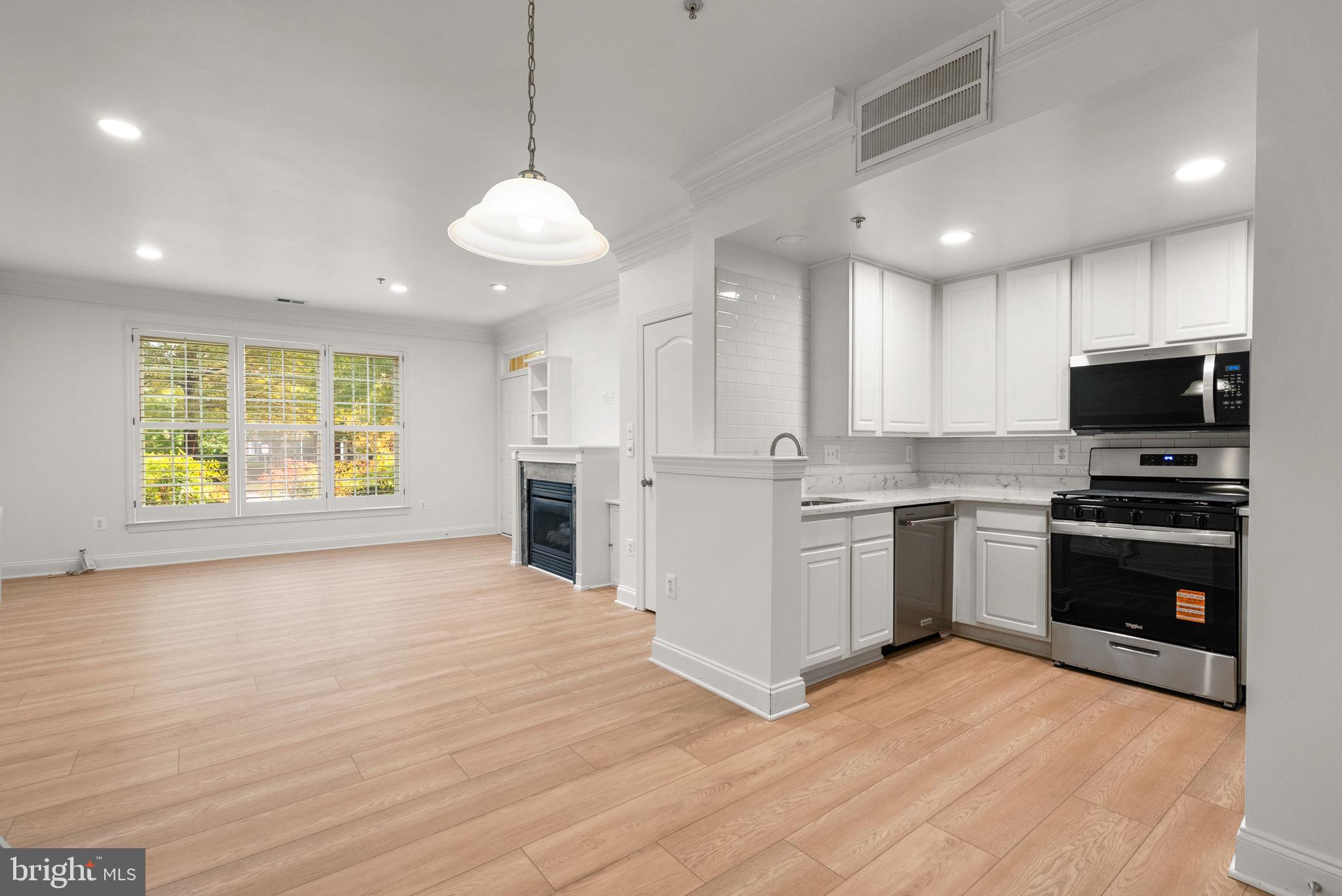 139 Chevy Chase Street, Unit 139 Gaithersburg, MD 20878 - Photo 9 of 27 a kitchen with stainless steel appliances granite countertop a stove top oven a sink and dishwasher with wooden floor