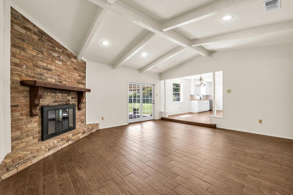 141 Travis Lane Hewitt, TX 76643 - Photo 7 of 31 Spacious living area featuring a brick fireplace with a wood mantle, vaulted ceilings with exposed beams, wood-finish flooring, and recessed lighting