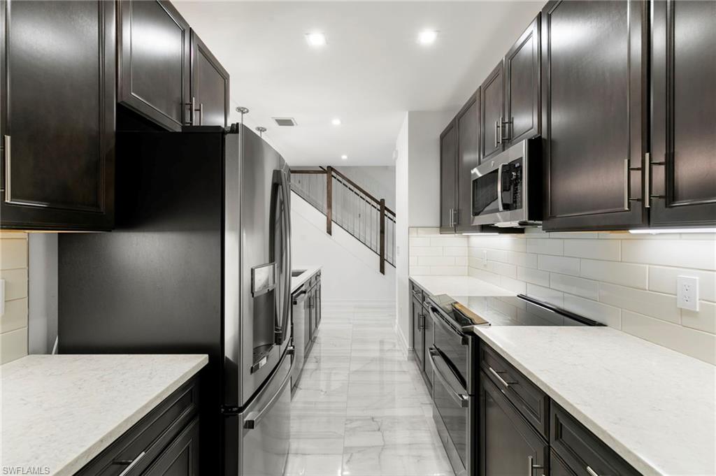 7572 Carnegie Way Naples, FL 34119 - Photo 15 of 43 a kitchen with granite countertop stainless steel appliances and wooden floor