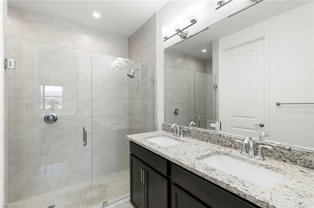 7572 Carnegie Way Naples, FL 34119 - Photo 19 of 43 a bathroom with a granite countertop sink a mirror and shower