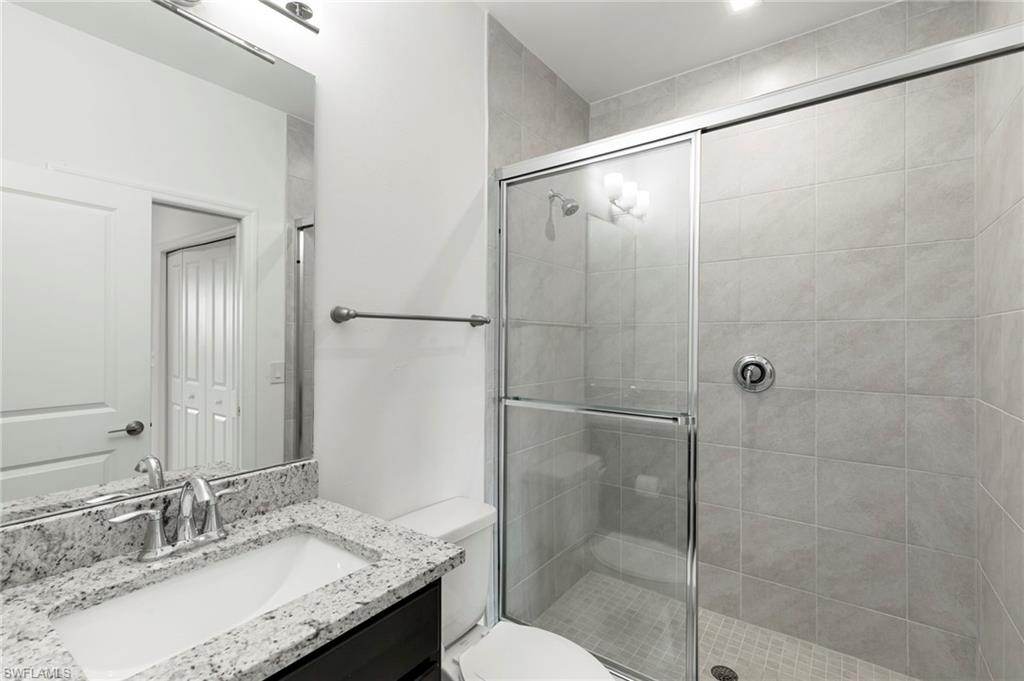 7572 Carnegie Way Naples, FL 34119 - Photo 24 of 43 a bathroom with a granite countertop shower sink vanity and toilet