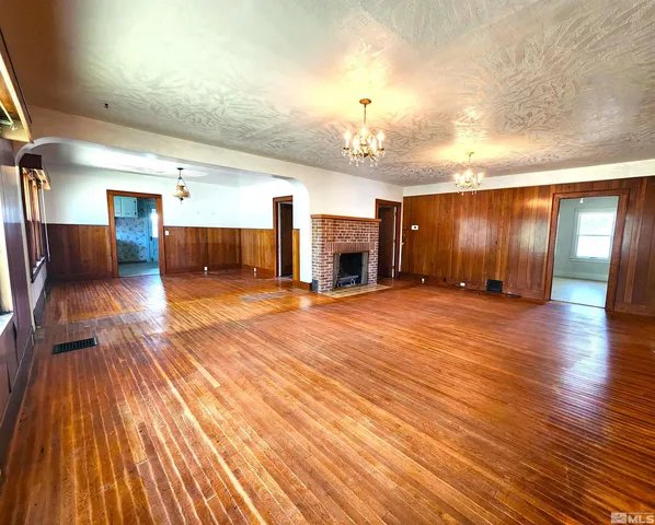 an empty room with wooden floor and chandelier