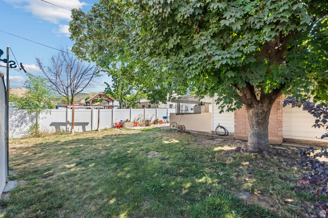31 B Street Springville, UT 84663 - Photo 28 of 31 Lawn area featuring a mature tree, white privacy fencing, and brick exterior elements
