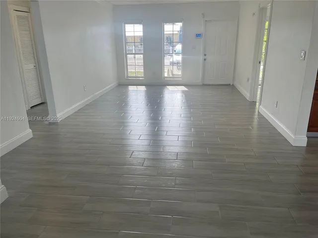 a view of an empty room with window and wooden floor