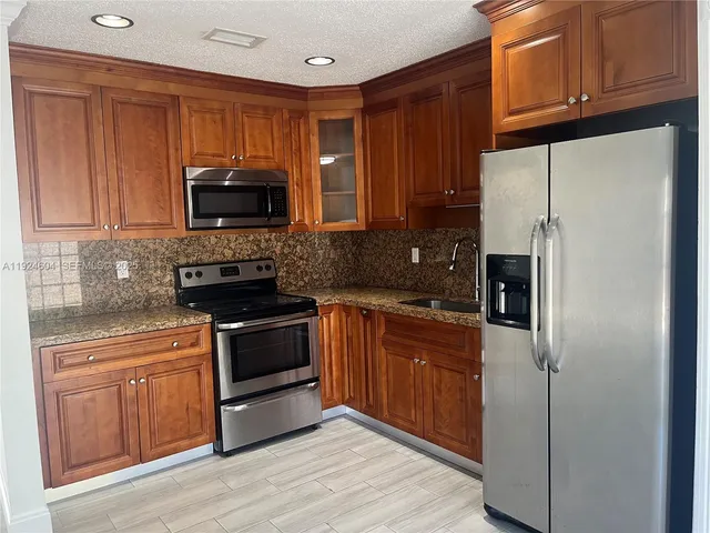 a kitchen with granite countertop wooden cabinets stainless steel appliances and a window