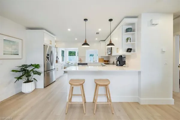 a kitchen with stainless steel appliances granite countertop a sink a stove a dining table and chairs