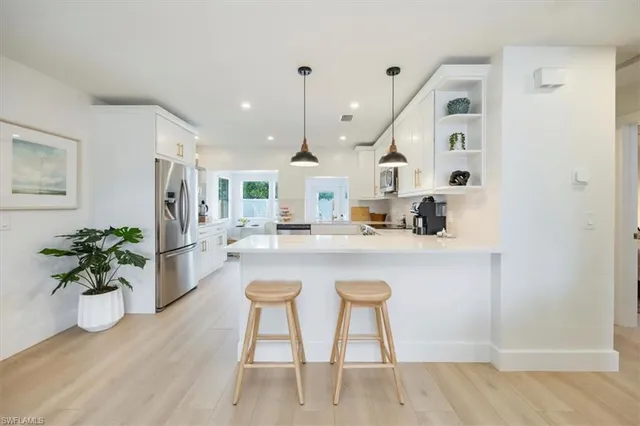 a kitchen with stainless steel appliances granite countertop a sink a stove a dining table and chairs