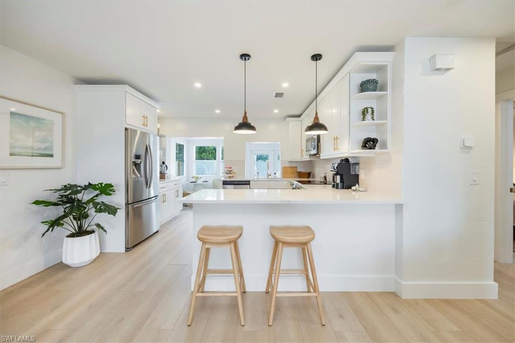4523 Fluvia Avenue Naples, FL 34103 - Photo 7 of 20 a kitchen with stainless steel appliances granite countertop a sink a stove a dining table and chairs