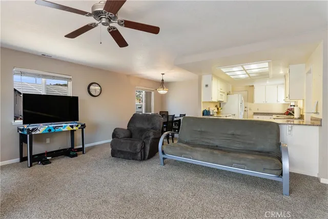 a living room with furniture ceiling fan and a large window