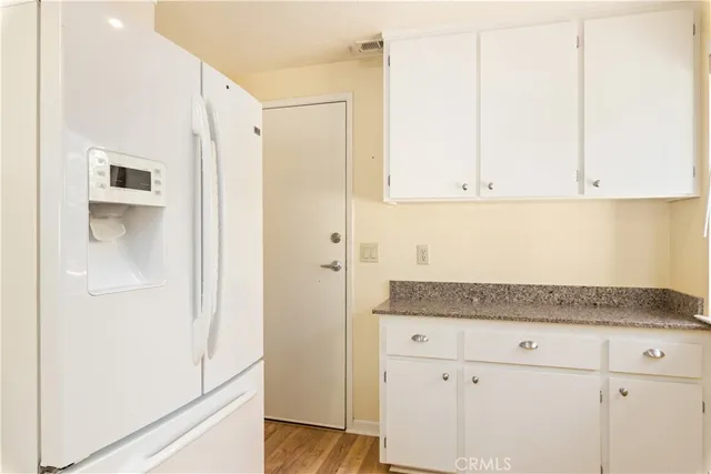 a kitchen with a stove a sink and white cabinets with wooden floor