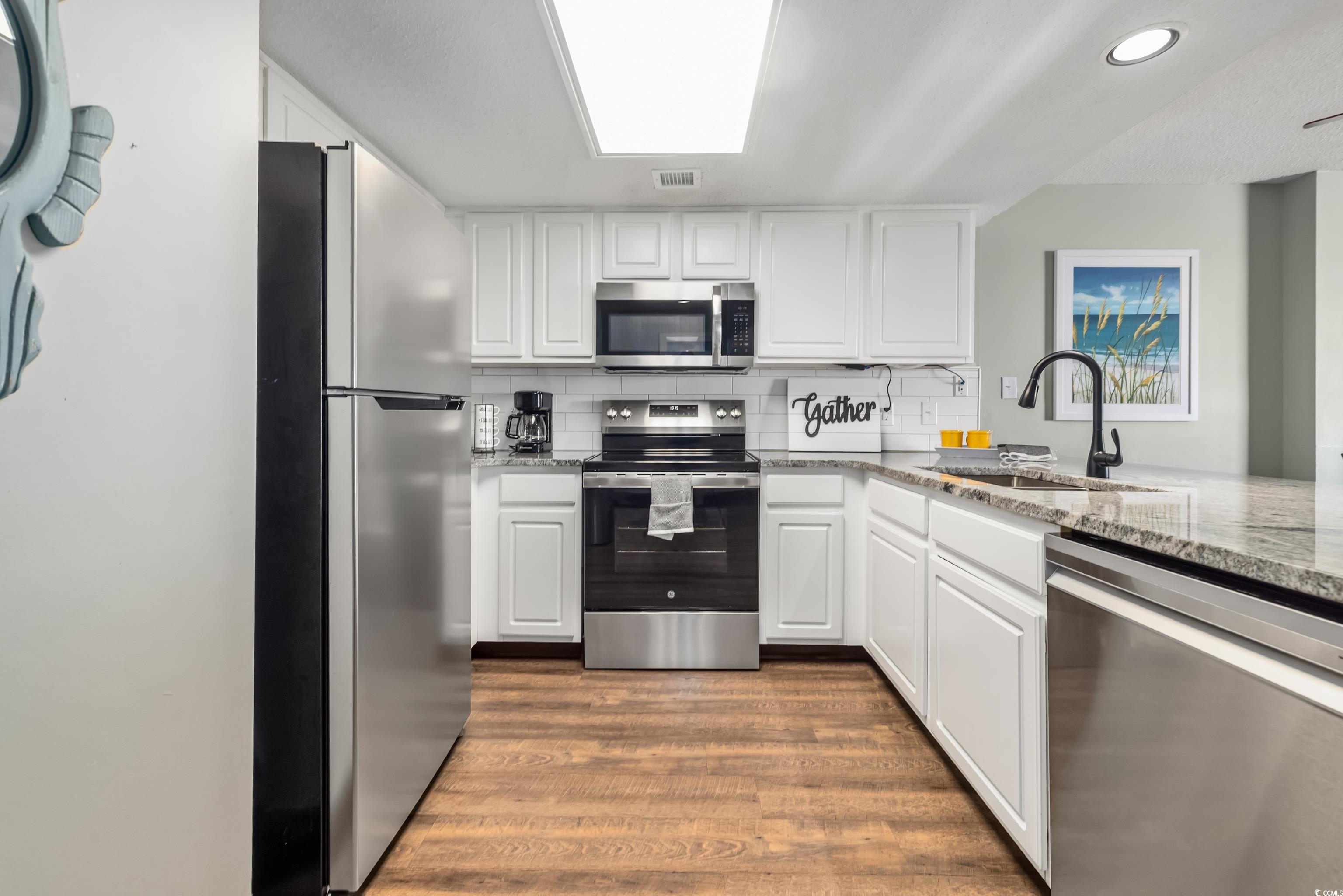 205 74th Avenue North, Unit 1104 Myrtle Beach, SC 29572 - Photo 15 of 40 Kitchen featuring appliances with stainless steel finishes, light stone counters, white cabinetry, tasteful backsplash, and dark wood finished floors