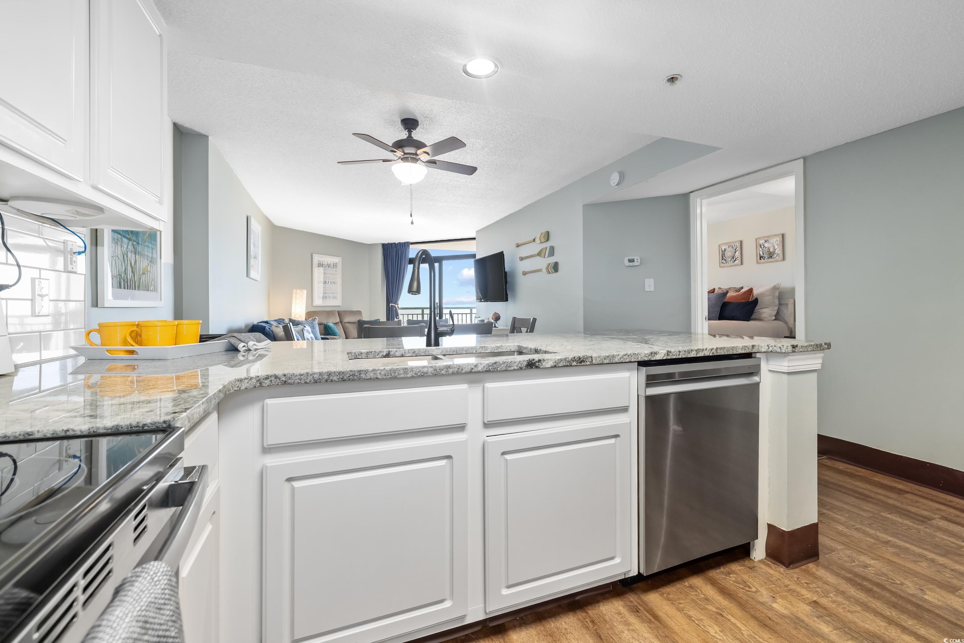 205 74th Avenue North, Unit 1104 Myrtle Beach, SC 29572 - Photo 40 of 40 Kitchen with white cabinetry, open floor plan, light wood-type flooring, and light stone counters