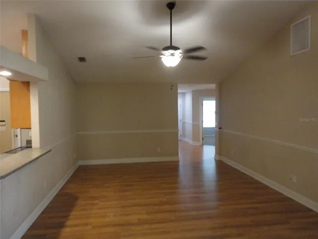 a view of empty room with wooden floor and fan