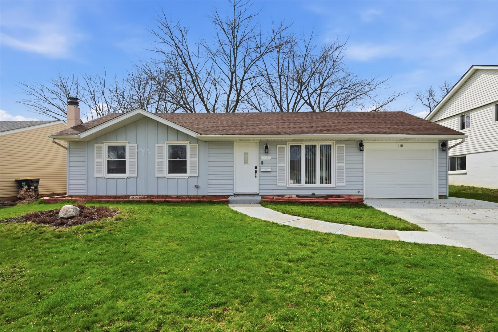 a view of a yard in front of a house with plants and large tree