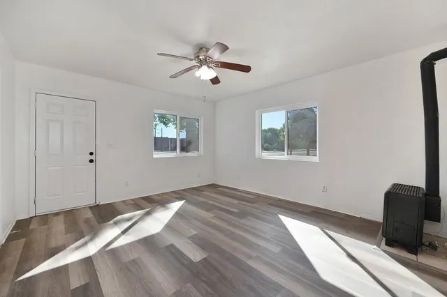 a view of empty room with wooden floor and fan