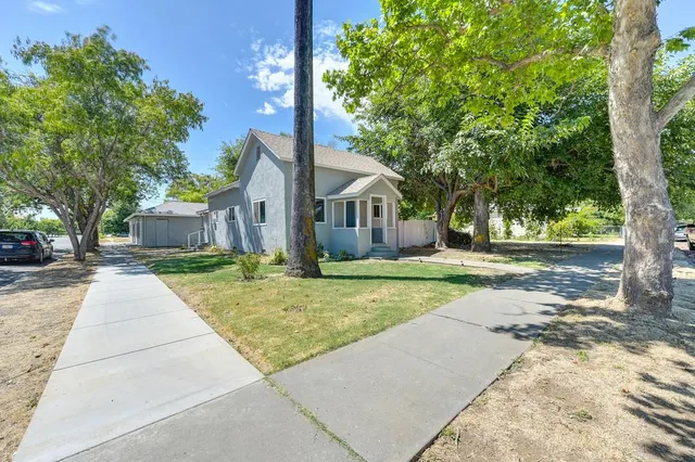 a front view of a house with a yard and trees