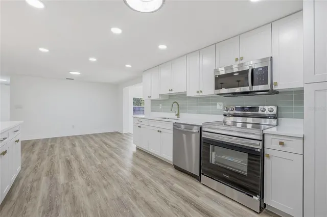 a kitchen with stainless steel appliances granite countertop a stove a sink and a microwave