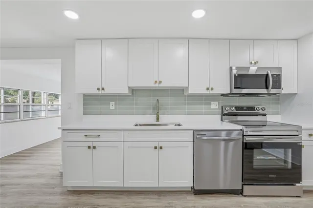 a kitchen with white cabinets stainless steel appliances and sink