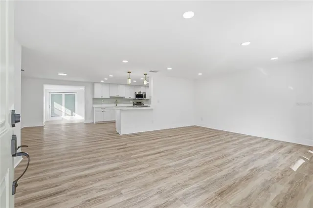 a view of kitchen and empty room with wooden floor