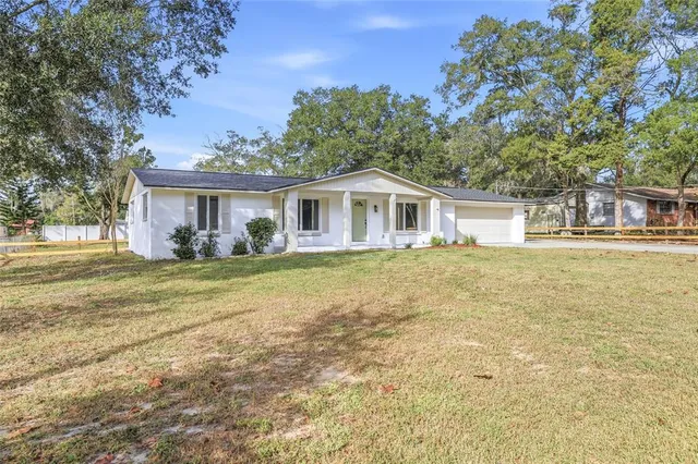 a front view of house with yard and trees in the background