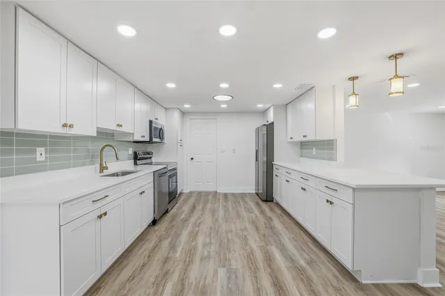 a large kitchen with granite countertop a large counter top a sink stainless steel appliances and cabinets