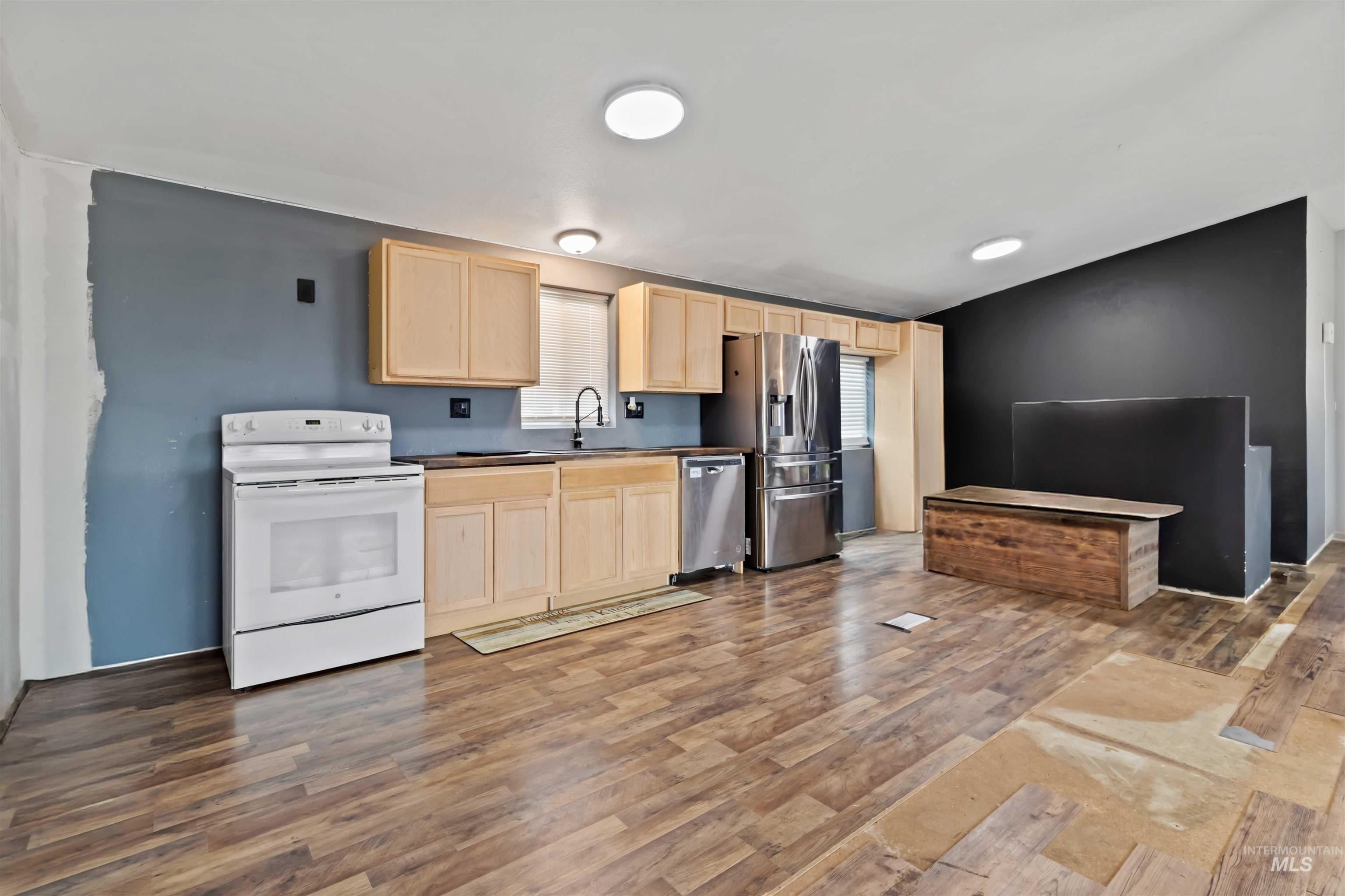5827 East Little Basin Road King Hill, ID 83633 - Photo 5 of 47 Kitchen featuring light brown cabinets, white range with electric stovetop, stainless steel dishwasher, light wood finished floors, and dark countertops