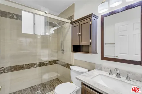 a bathroom with a granite countertop sink toilet and shower