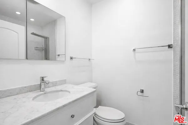 a kitchen with stainless steel appliances granite countertop a sink a stove top oven a refrigerator cabinets and living room view