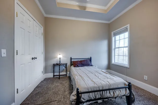 a bedroom with a bed table flat screen tv and a window