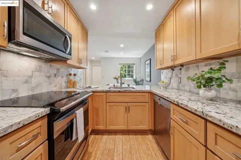 a kitchen with granite countertop stainless steel appliances stove microwave and cabinets