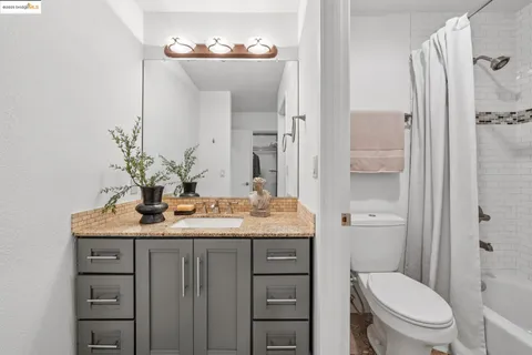 a bathroom with a granite countertop sink toilet a mirror and shower