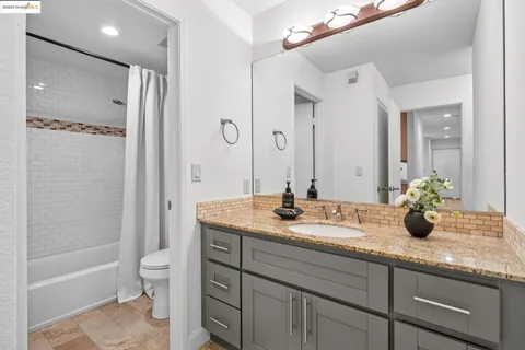 a bathroom with a granite countertop sink mirror toilet and bathtub