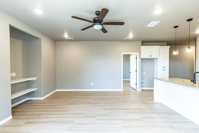 a view of empty room with wooden floor and ceiling fan
