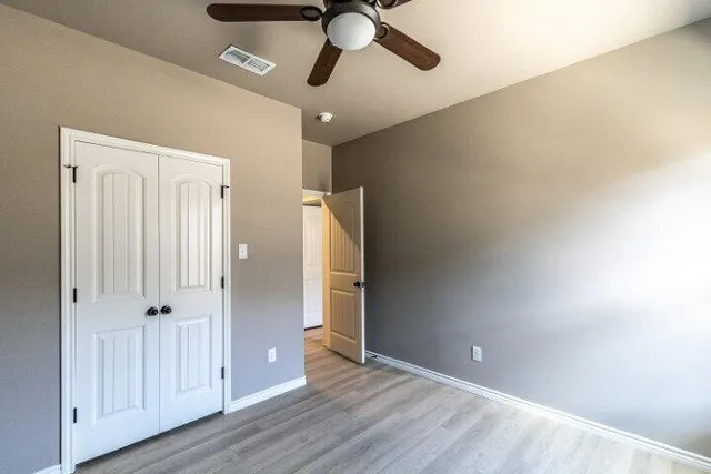 an empty room with wooden floor closet and windows