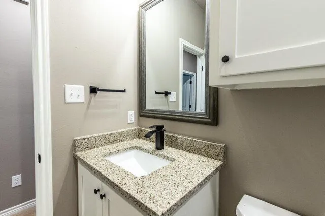 a bathroom with a granite countertop sink and a mirror