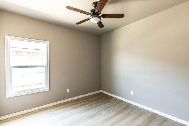 an empty room with a window and a fan
