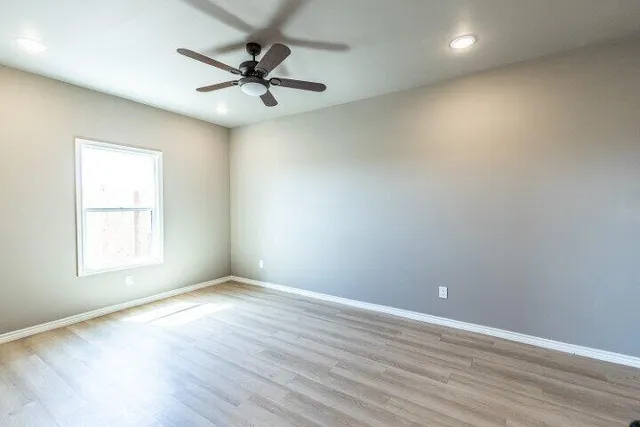 an empty room with a window and a ceiling fan
