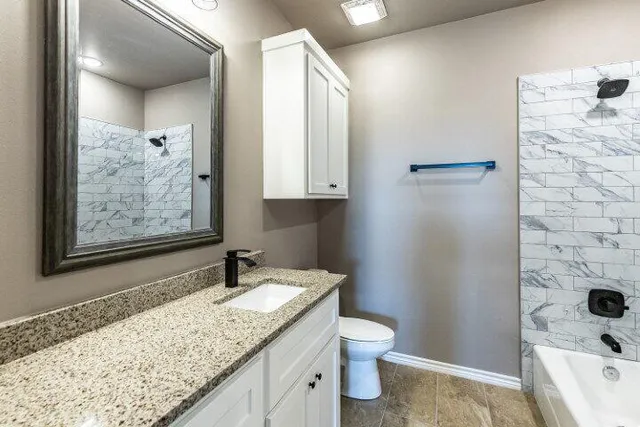 a bathroom with a granite countertop sink toilet and shower