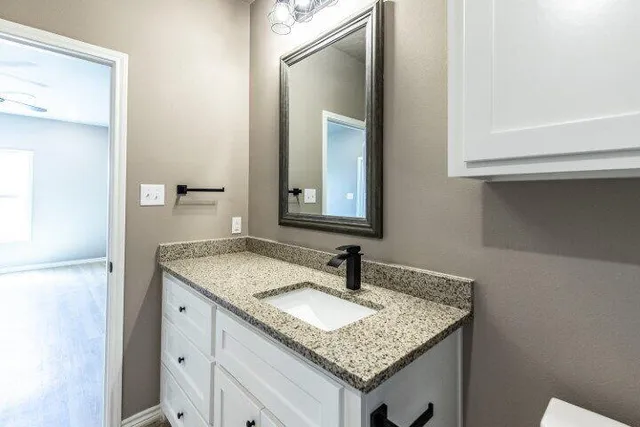 a bathroom with a granite countertop sink and a mirror