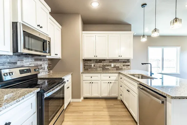 a kitchen with stainless steel appliances granite countertop a sink stove and microwave