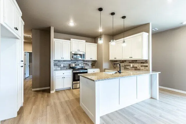 a kitchen with kitchen island granite countertop a sink cabinets and wooden floor
