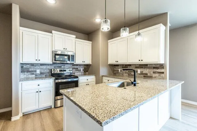 a kitchen with stainless steel appliances granite countertop a sink a stove and a microwave