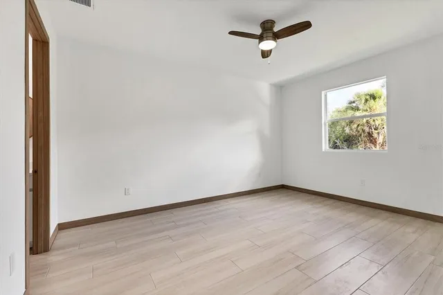 an empty room with windows and ceiling fan