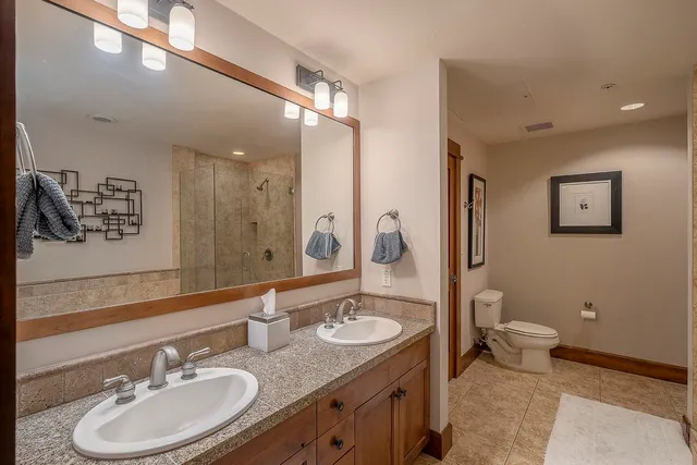 a bathroom with a granite countertop sink a mirror and a toilet