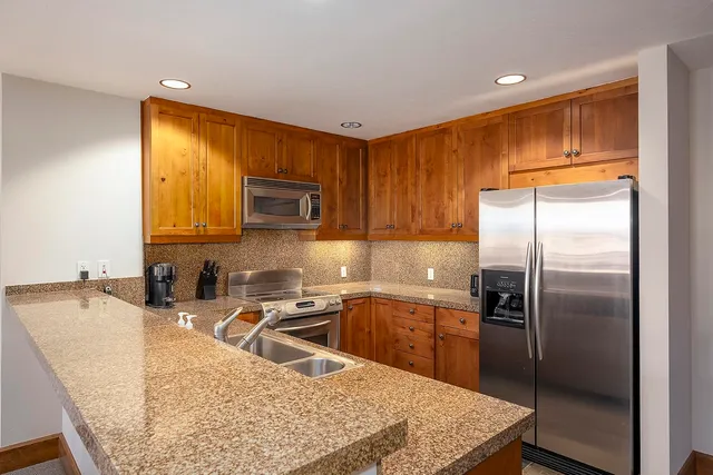a kitchen with stainless steel appliances granite countertop a sink a microwave a refrigerator and a stove