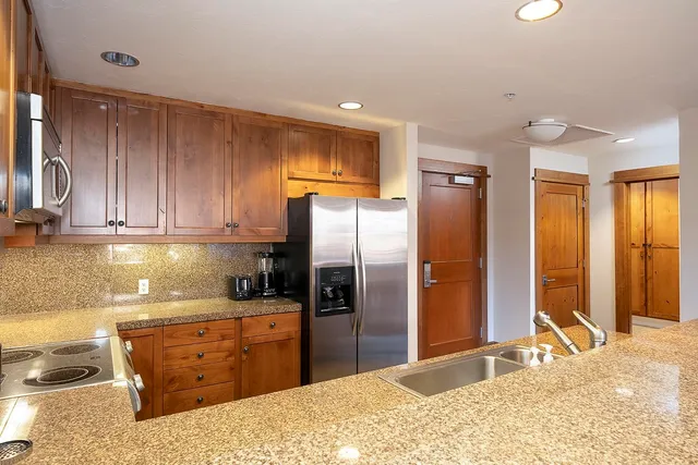 a kitchen with stainless steel appliances kitchen island granite countertop a refrigerator oven a sink with granite countertops and couches